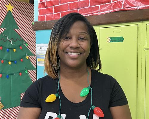 Teacher wearing black shirt with yellow, green and red Christmas lights.